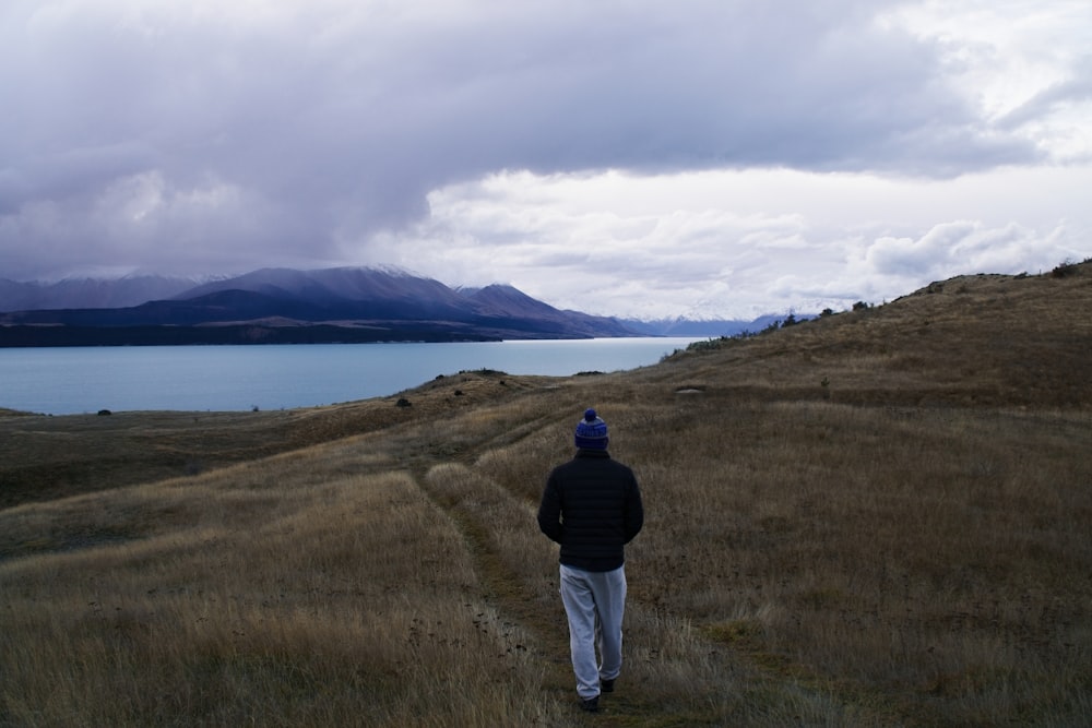 a man walking down a path towards a body of water
