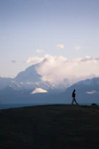 Golden hour light casting long shadows on a mountain ridge where a lone walker uses the hypershell exoskeleton