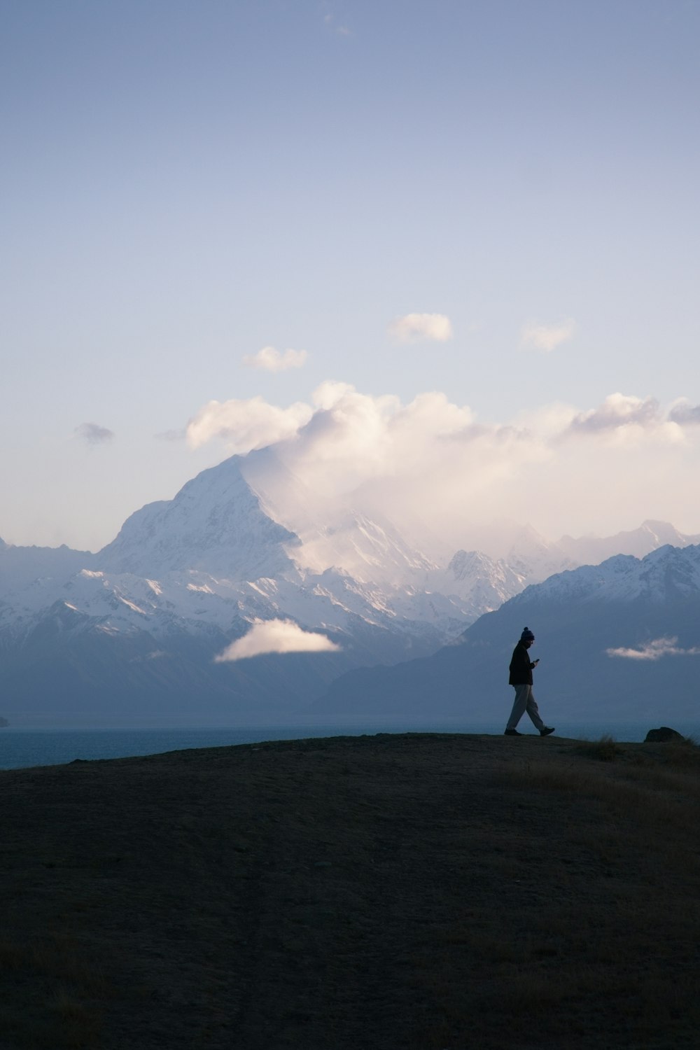 a person walking on top of a grass covered hill