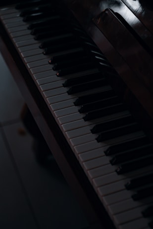 Black and white photo of a grand piano keyboard with soft natural light highlighting the keys.