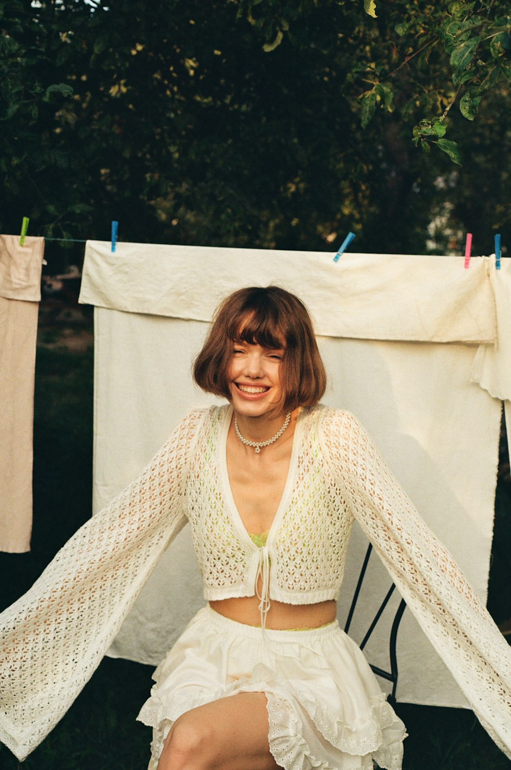 a woman sitting on a chair in front of a clothes line