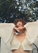 A joyful woman wearing layered bracelets and smiling in a sunlit outdoor setting