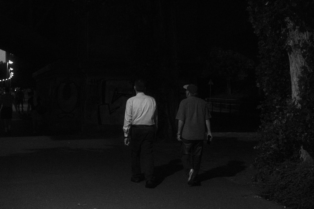 a couple of men walking down a street at night