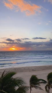 Sunset casting warm golden light over the palm trees and crystal-clear sea at Cayo Levantado.