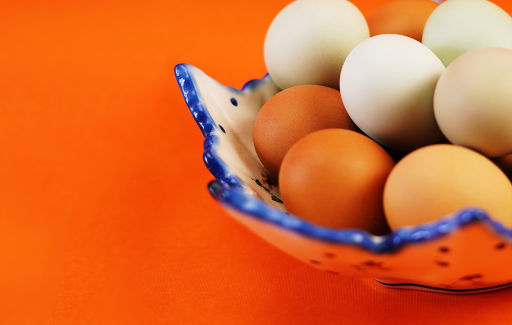 a blue and white bowl filled with brown and white eggs