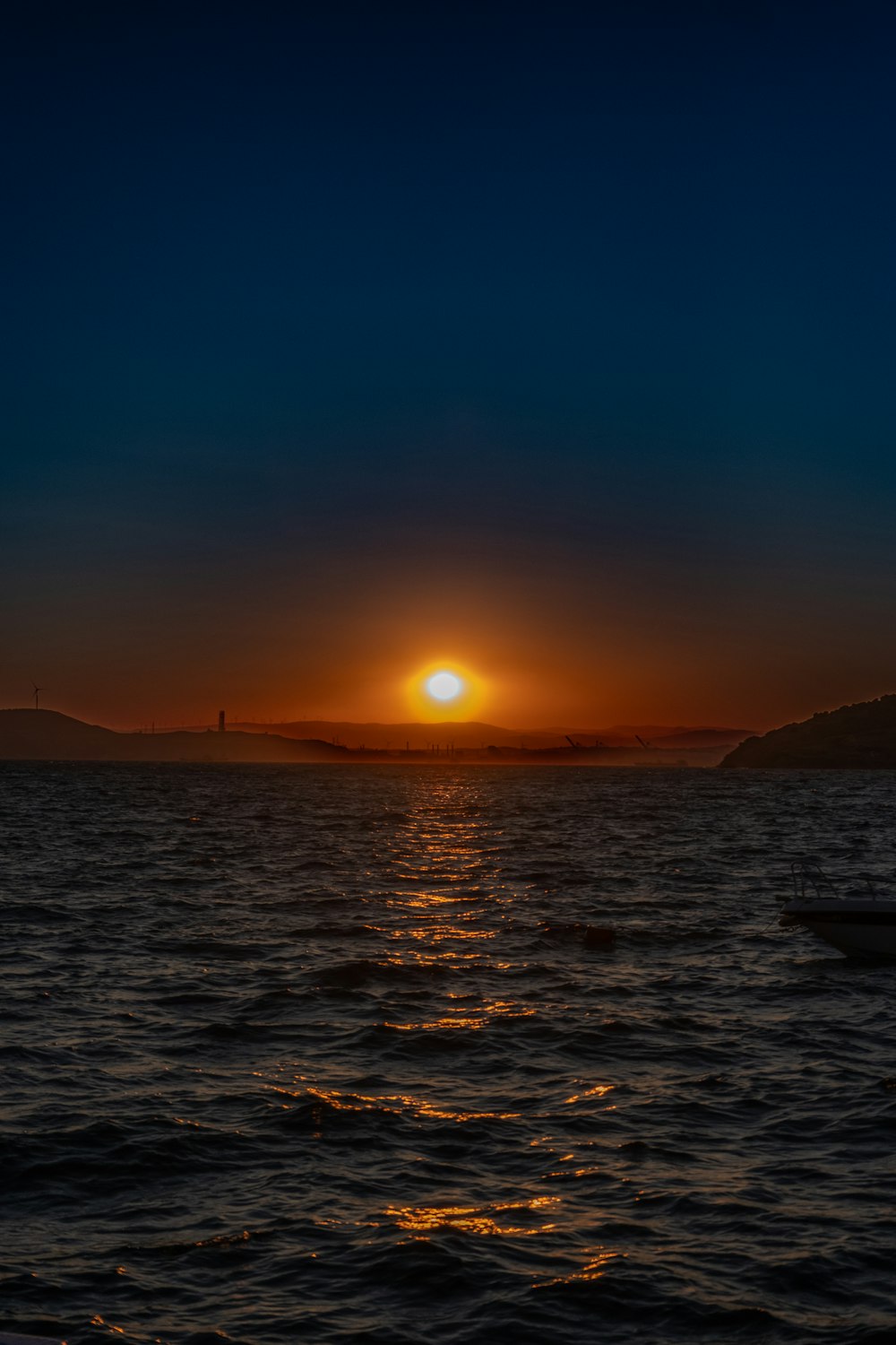 the sun is setting over the ocean with a boat in the water