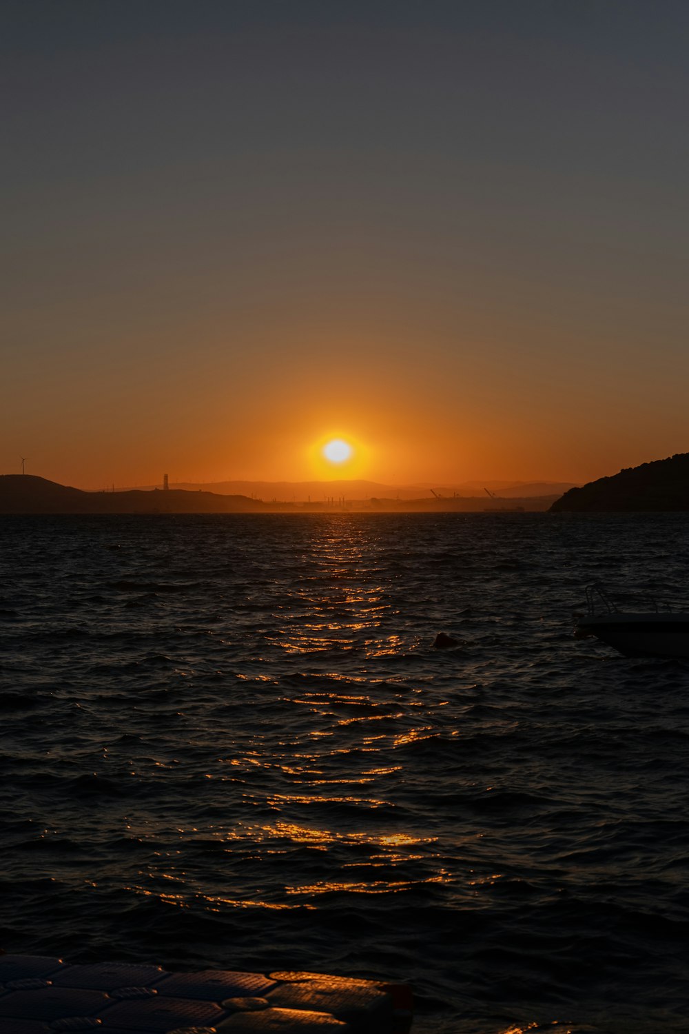 the sun setting over the ocean with a boat in the water