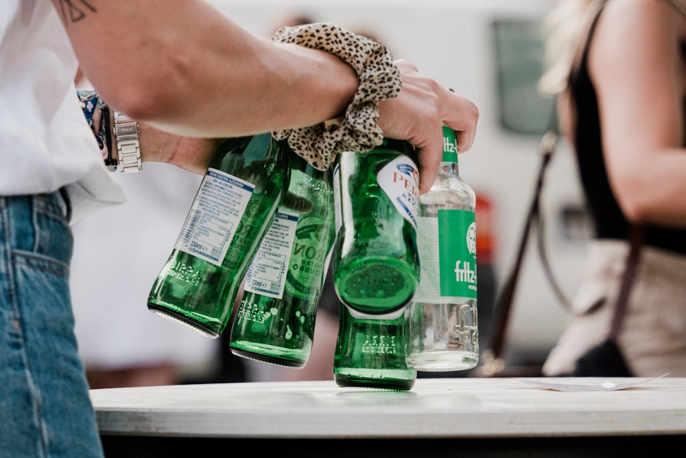 a group of people standing around a table with green bottles
