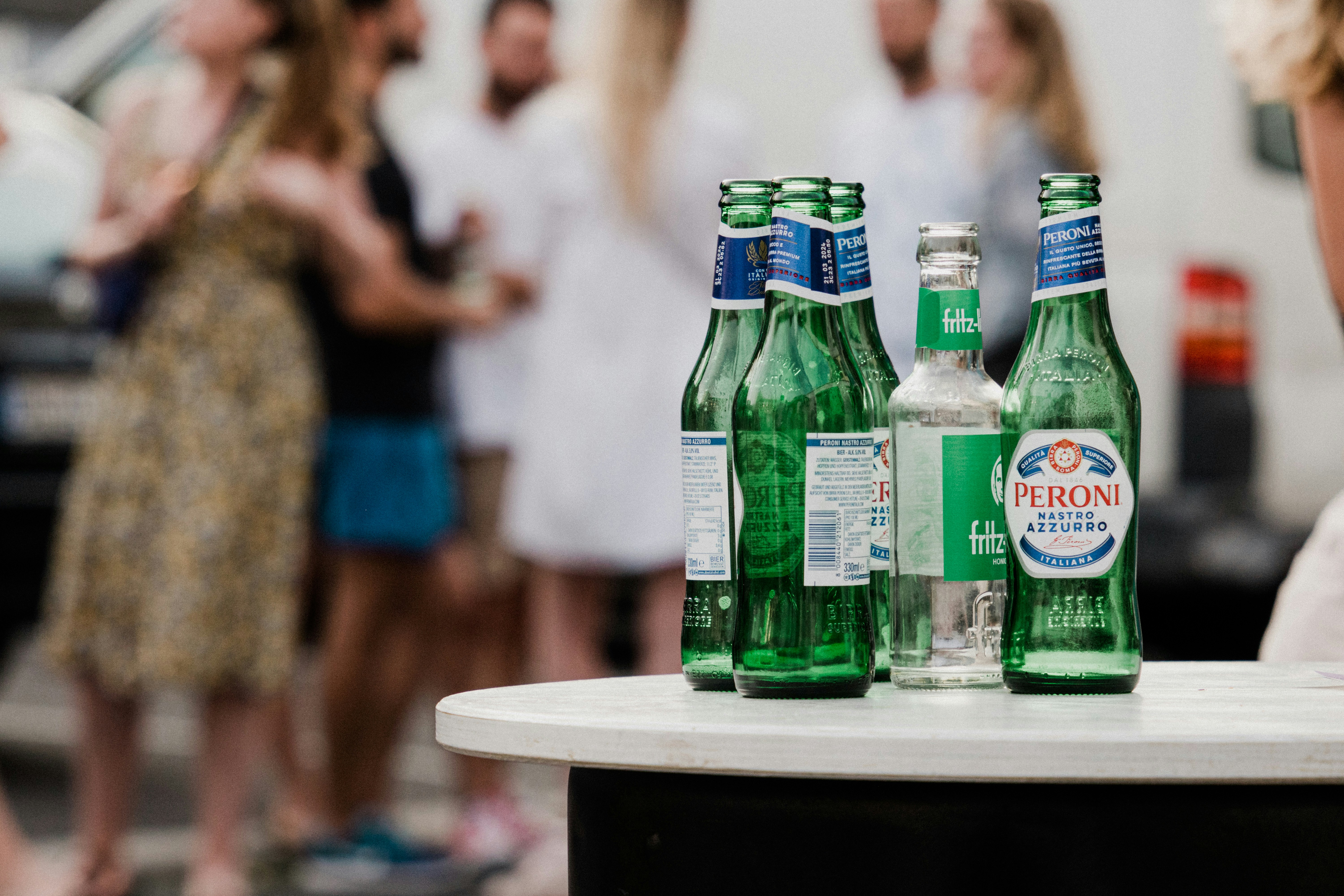 A group of people standing around a table with bottles of beer photo