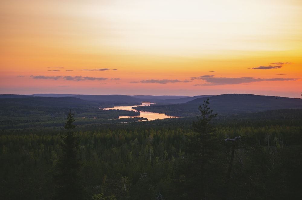 a sunset view of a lake and a forest