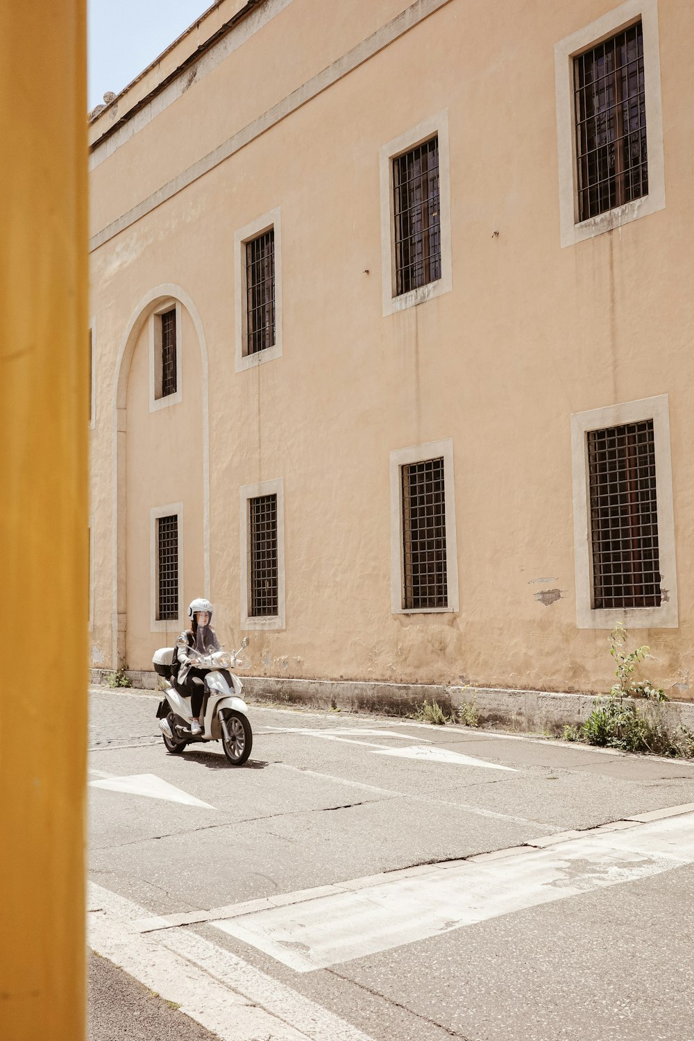 a man riding a motorcycle down a street next to a tall building