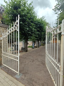 a white iron gate on a brick walkway