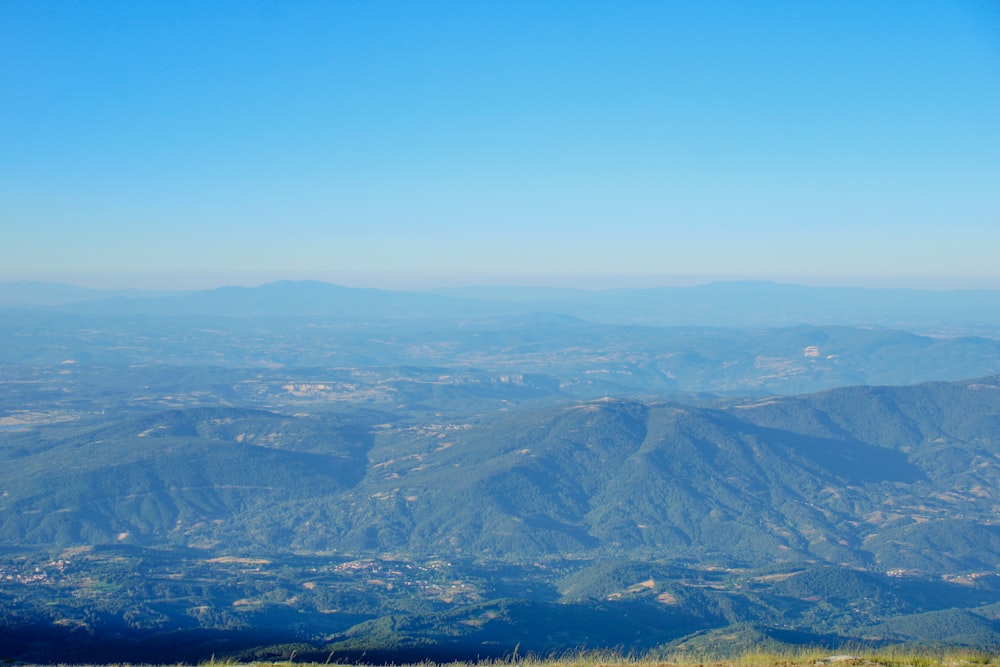 a view of a valley and mountains from a hill