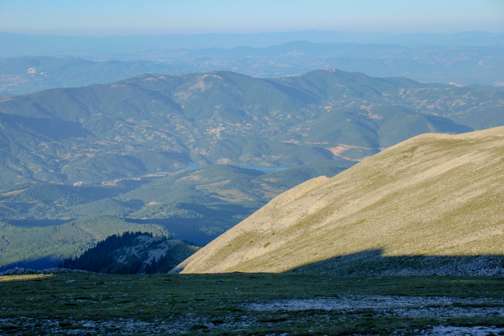 Una persona in piedi sulla cima di una collina con le montagne sullo sfondo