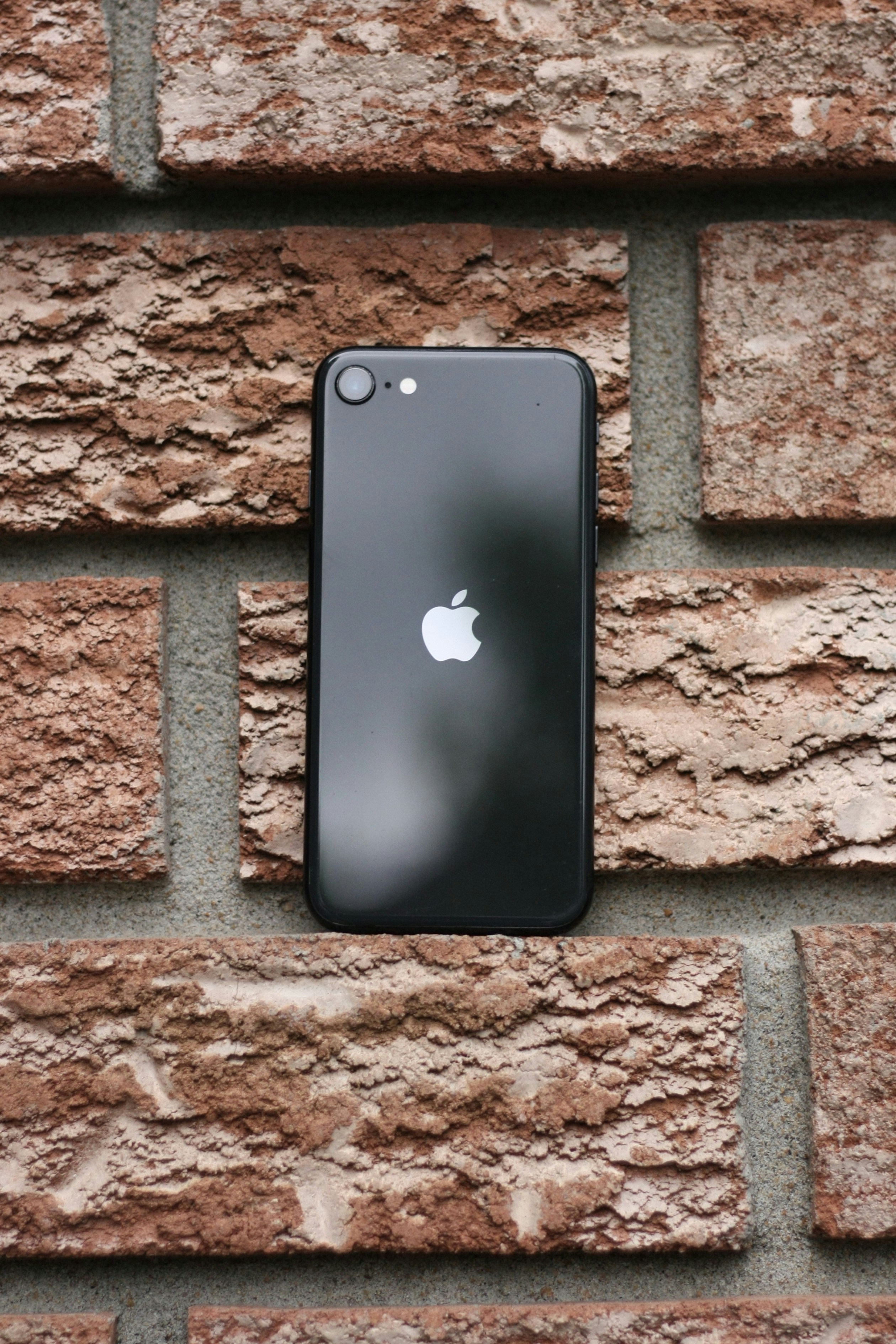 a black iphone sitting on top of a brick wall