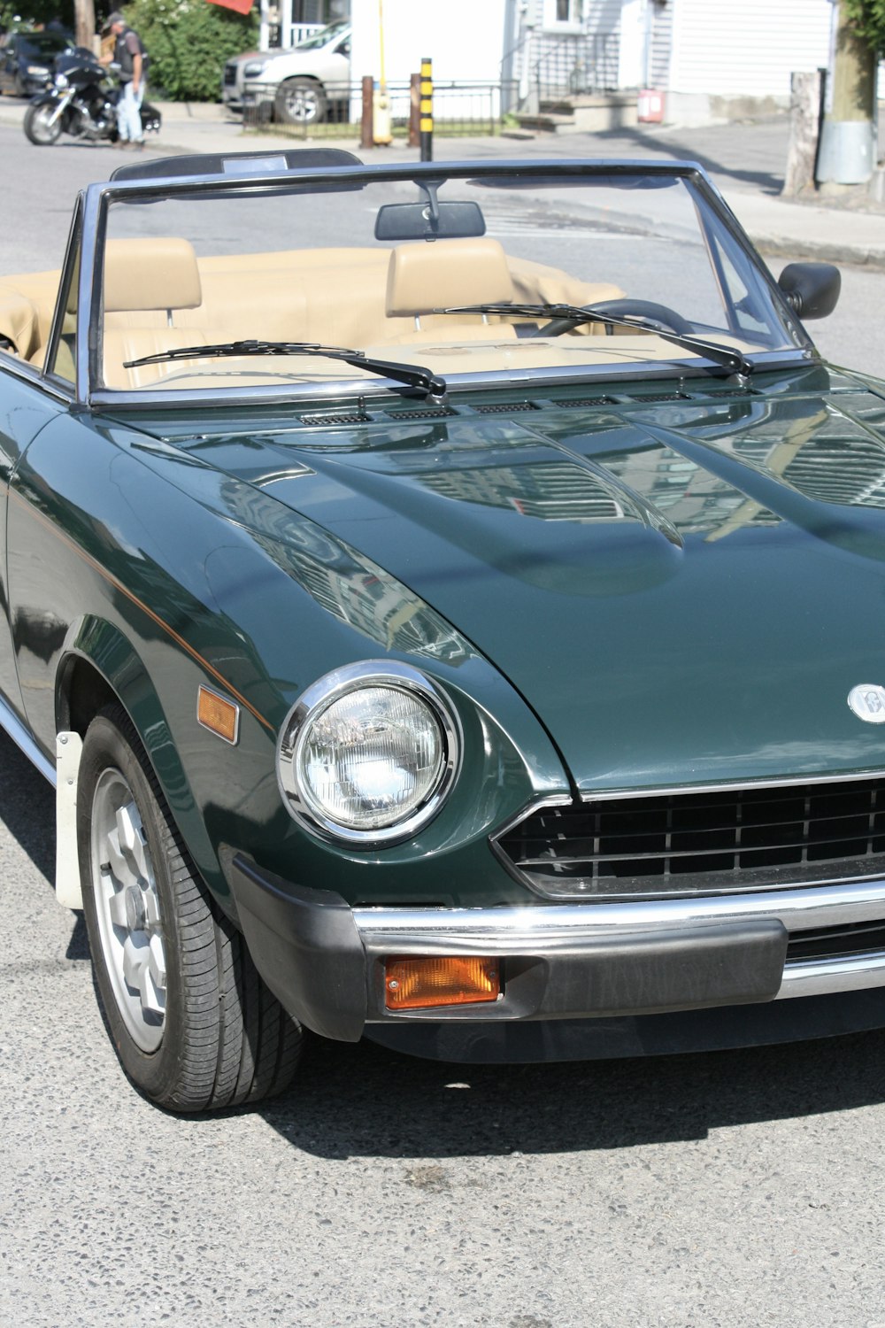 a green convertible car parked on the side of the road