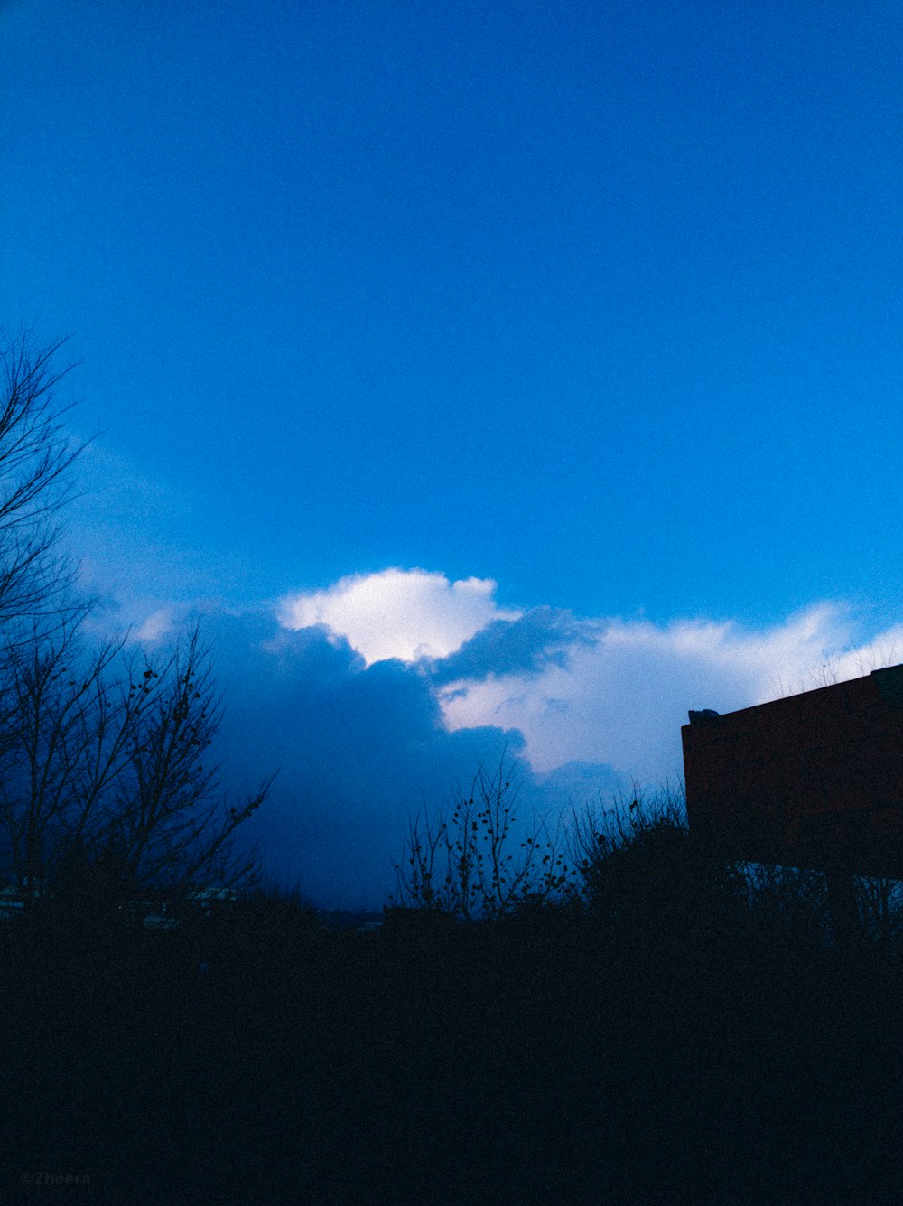 a blue sky with clouds and a bench in the foreground