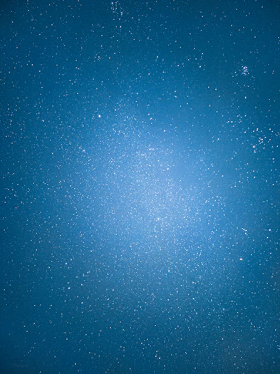 A serene night sky with glowing zodiac constellations and a golden mandala pattern softly illuminated in deep blue.