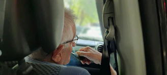 Happy senior citizen enjoying music from an SRS car radio in their car.
