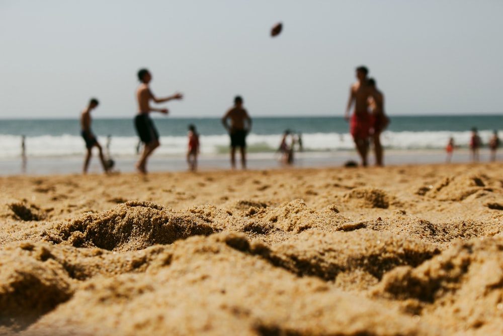 a group of people on a beach playing frisbee