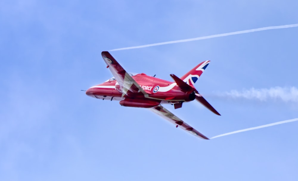 Un jet rojo y blanco volando a través de un cielo azul