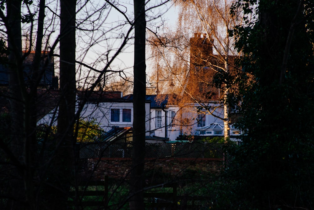 a house is seen through the trees in the evening