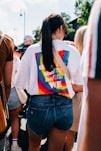 a woman wearing a rainbow shirt and denim shorts