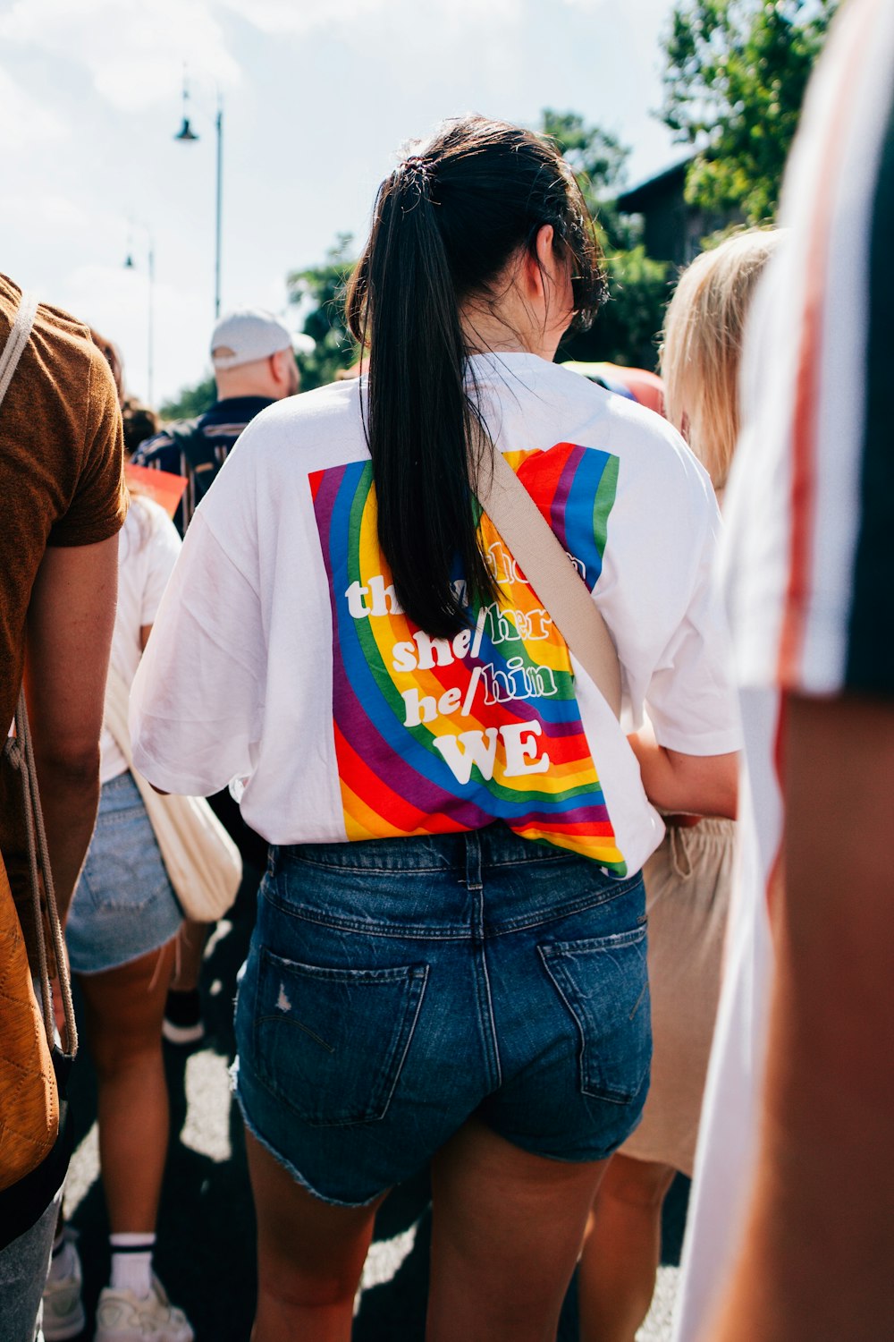 a woman wearing a rainbow shirt and denim shorts