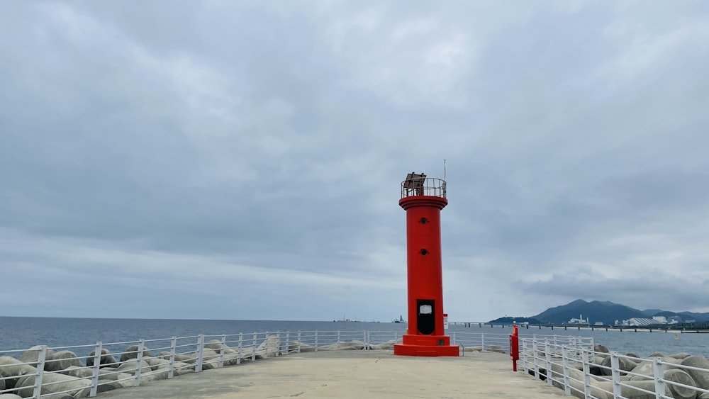 a red light house sitting on top of a pier