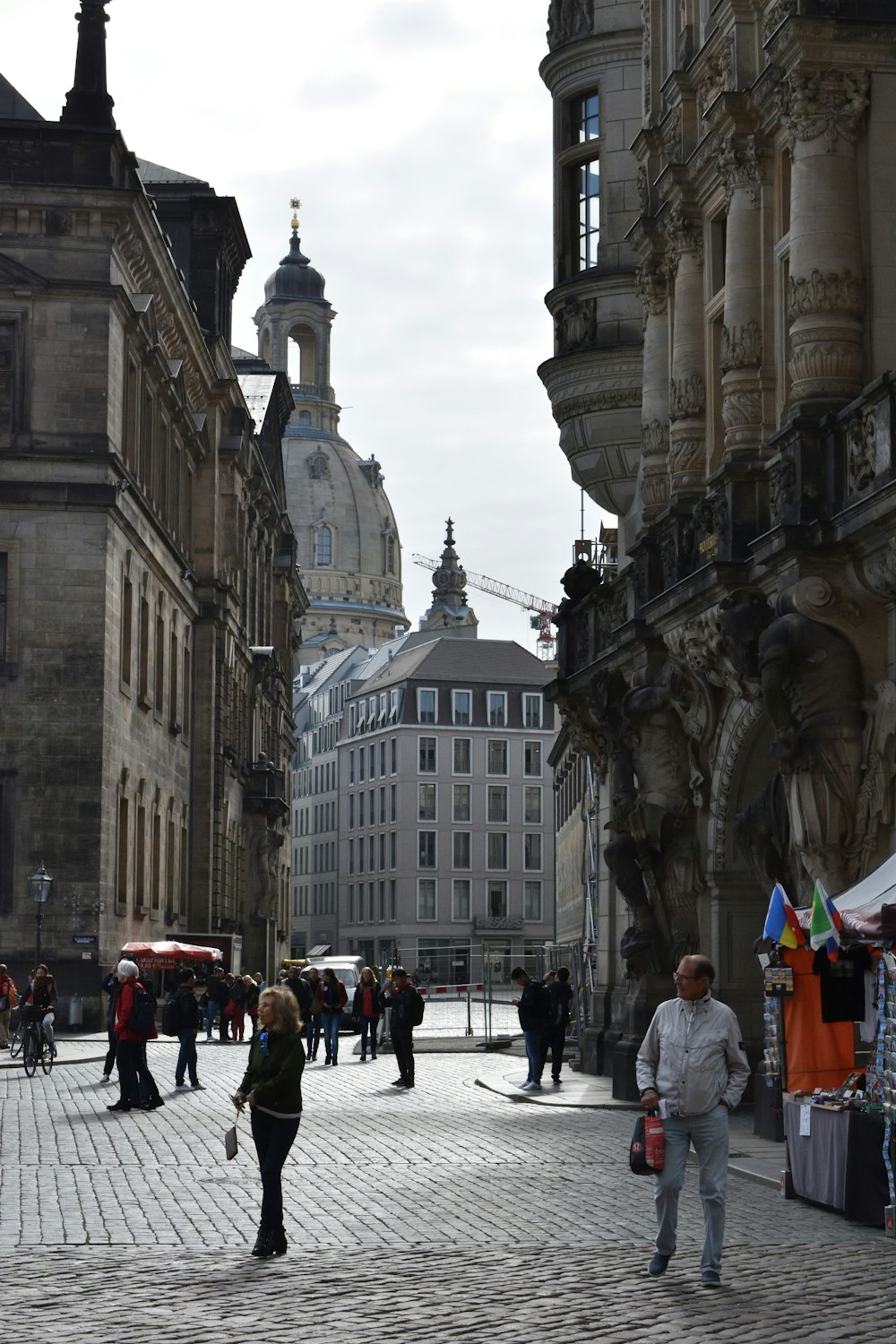 a group of people walking down a street next to tall buildings