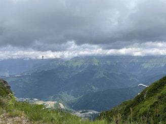 Adventurous hikers crossing a wooden bridge over a lush green valley.