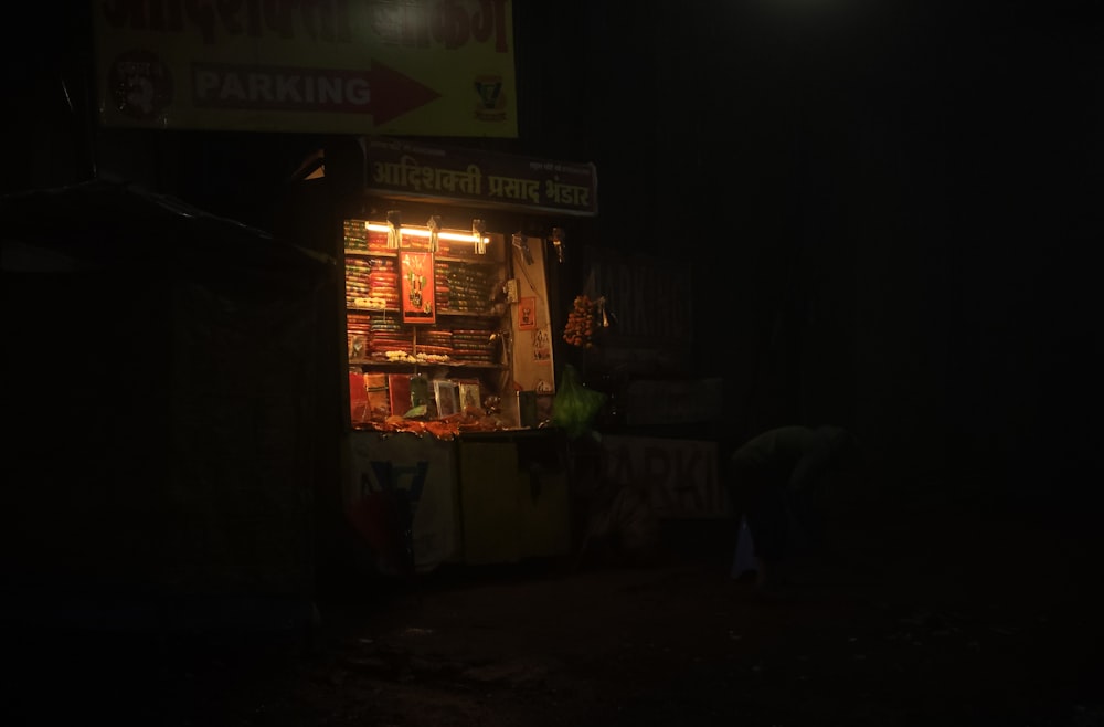 a dark street at night with a food stand lit up