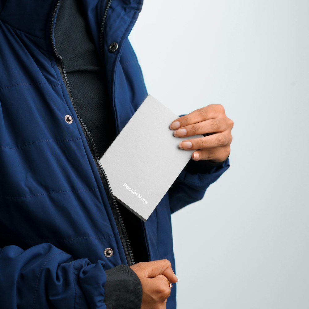 a person in a blue jacket holding a book