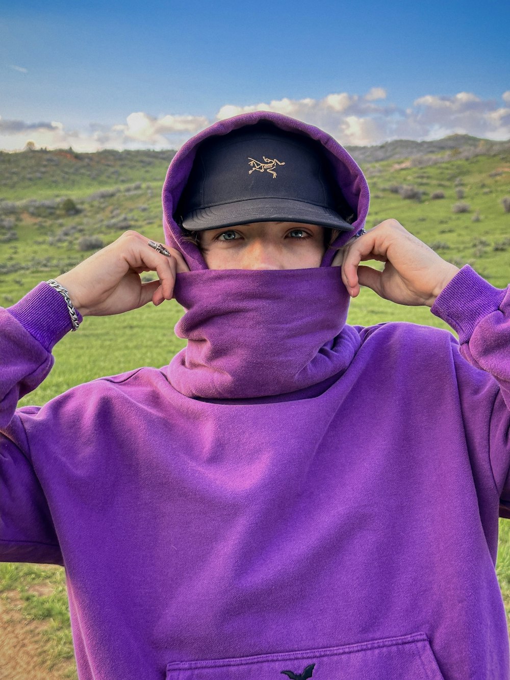 a person in a purple jacket and hat covering their face