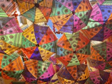 A vibrant assortment of nimbusia umbrellas hanging in natural daylight, highlighting various colors and patterns.