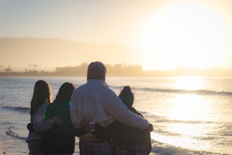 A warm, golden hour photo of a small group sharing a light moment during a morning run by the sea.