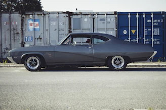 A sleek American muscle car being carefully loaded onto a shipping container.