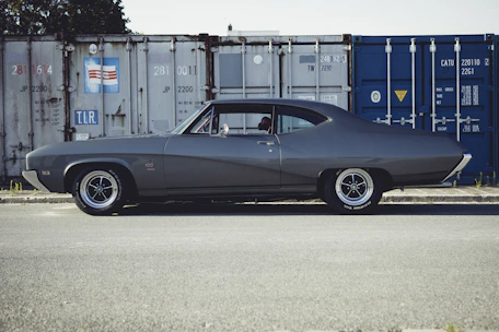 A sleek American muscle car being carefully loaded onto a shipping container.