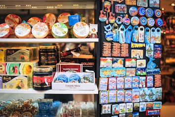 A display of various products, including packaged food items, decorative magnets, and other small merchandise. The products are neatly arranged on shelves, with colorful packaging and labels that catch the eye. On the right, a collection of magnets with images and text related to Istanbul are prominently featured.