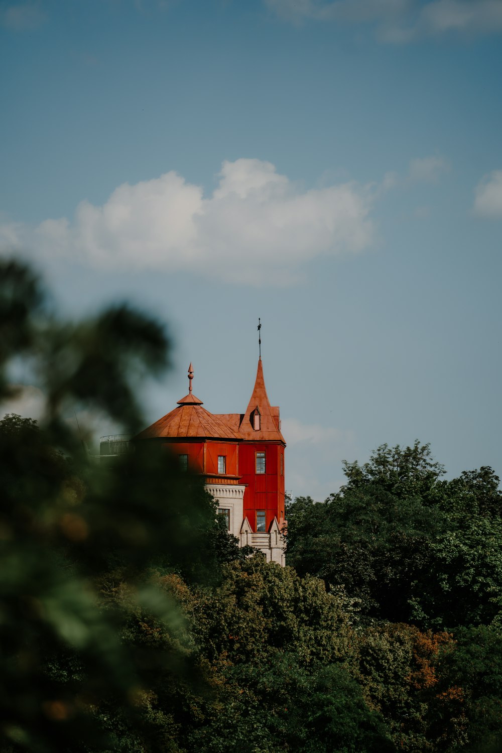 a red building with a steeple surrounded by trees