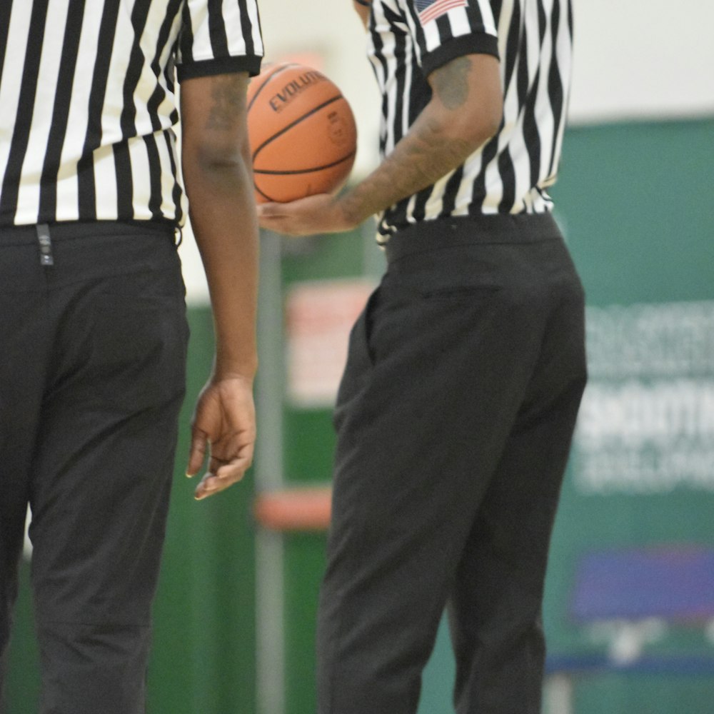 two men standing next to each other holding a basketball