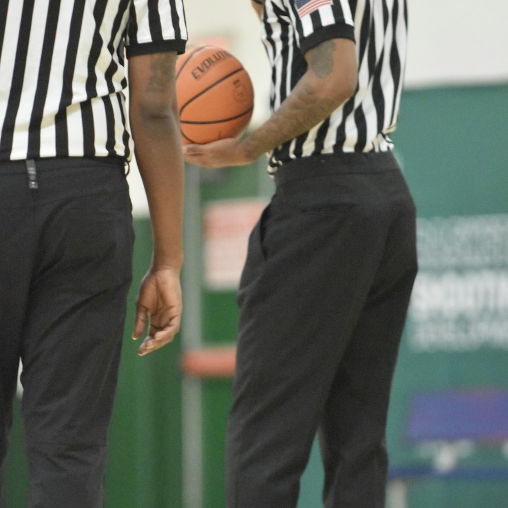 dois homens em pé um ao lado do outro segurando uma bola de basquete