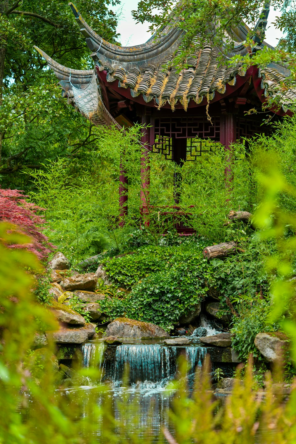 a garden with a waterfall and a gazebo