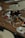 Various electronic components and metallic parts are scattered on a wooden surface, including circuit board pieces, screws, and circular metal rings.