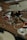 Various electronic components and metallic parts are scattered on a wooden surface, including circuit board pieces, screws, and circular metal rings.