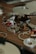 Various electronic components and metallic parts are scattered on a wooden surface, including circuit board pieces, screws, and circular metal rings.