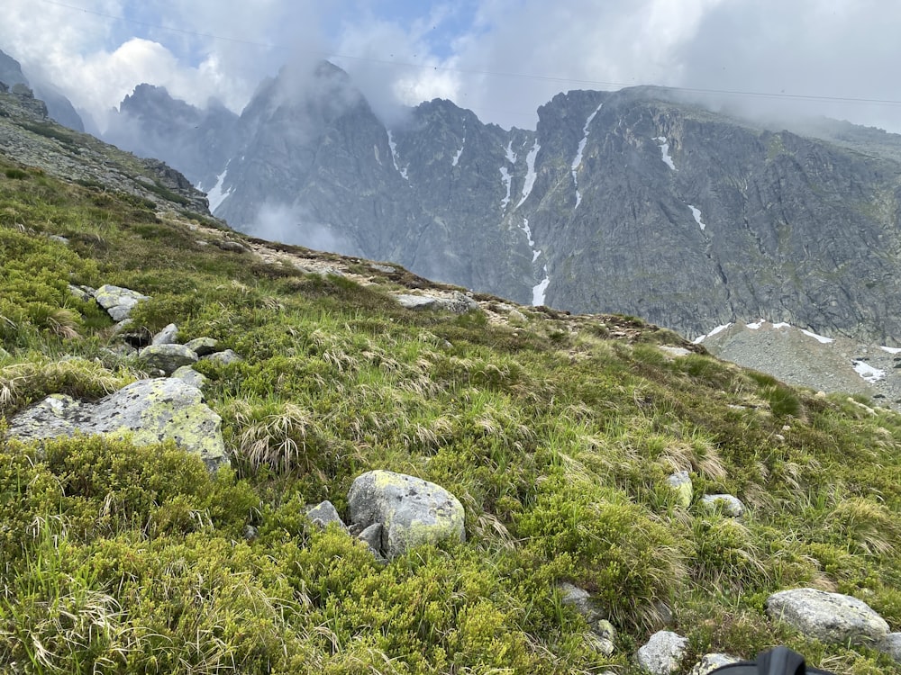 a person hiking up a grassy hill with mountains in the background