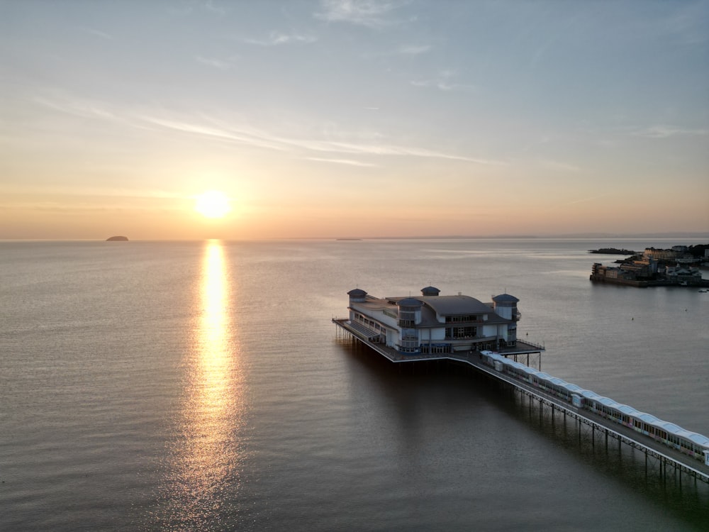 a pier with a house on it at sunset