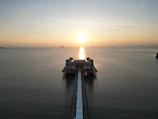 Wide shot of a waterfront pier at sunset, reflecting calm waters and clear skies.