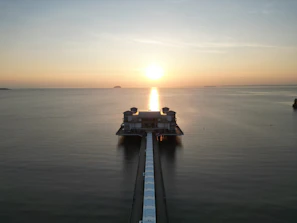 Wide shot of a waterfront pier at sunset, reflecting calm waters and clear skies.